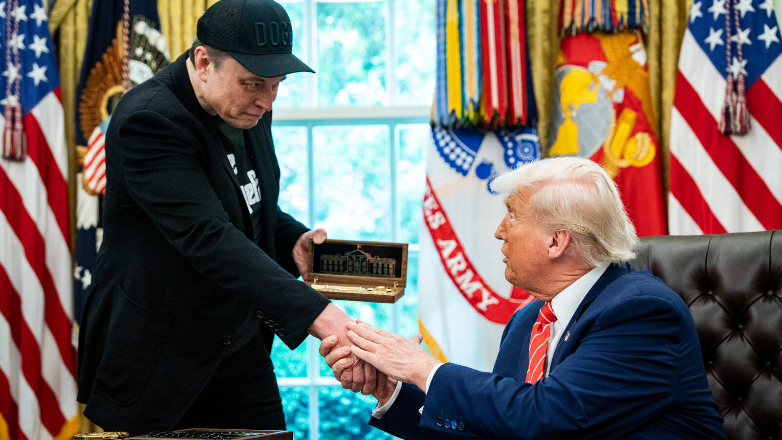 Donald Trump hands a ceremonial box to Elon Musk during a White House event
