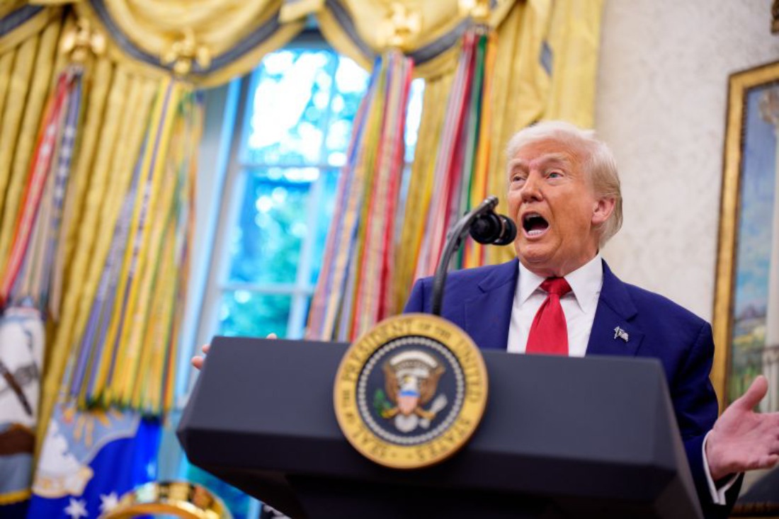 Donald Trump speaks animatedly at the presidential podium in the Oval Office, appearing mid-sentence during a fiery address