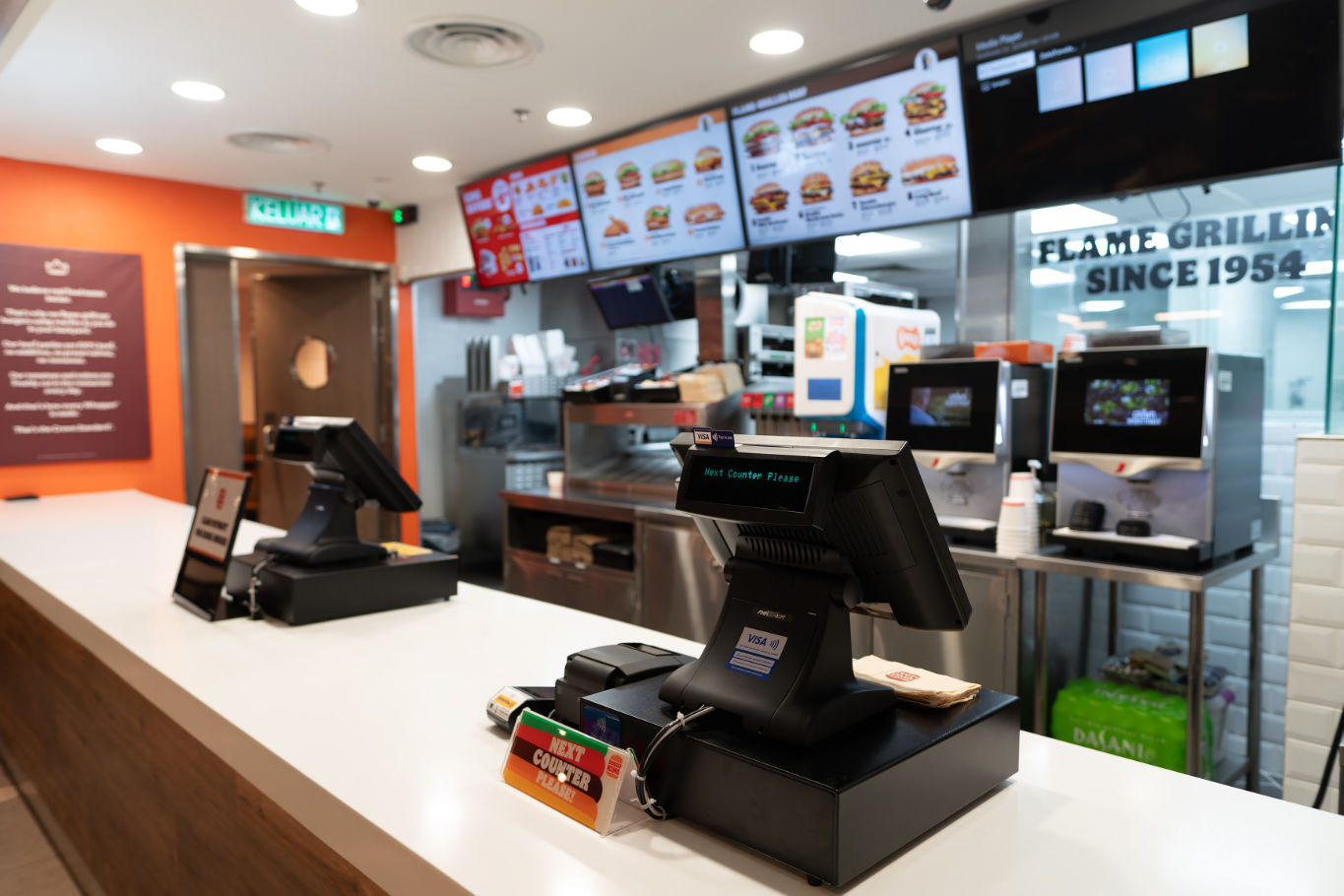 Empty fast food restaurant counter with touchscreen registers and digital menus visible