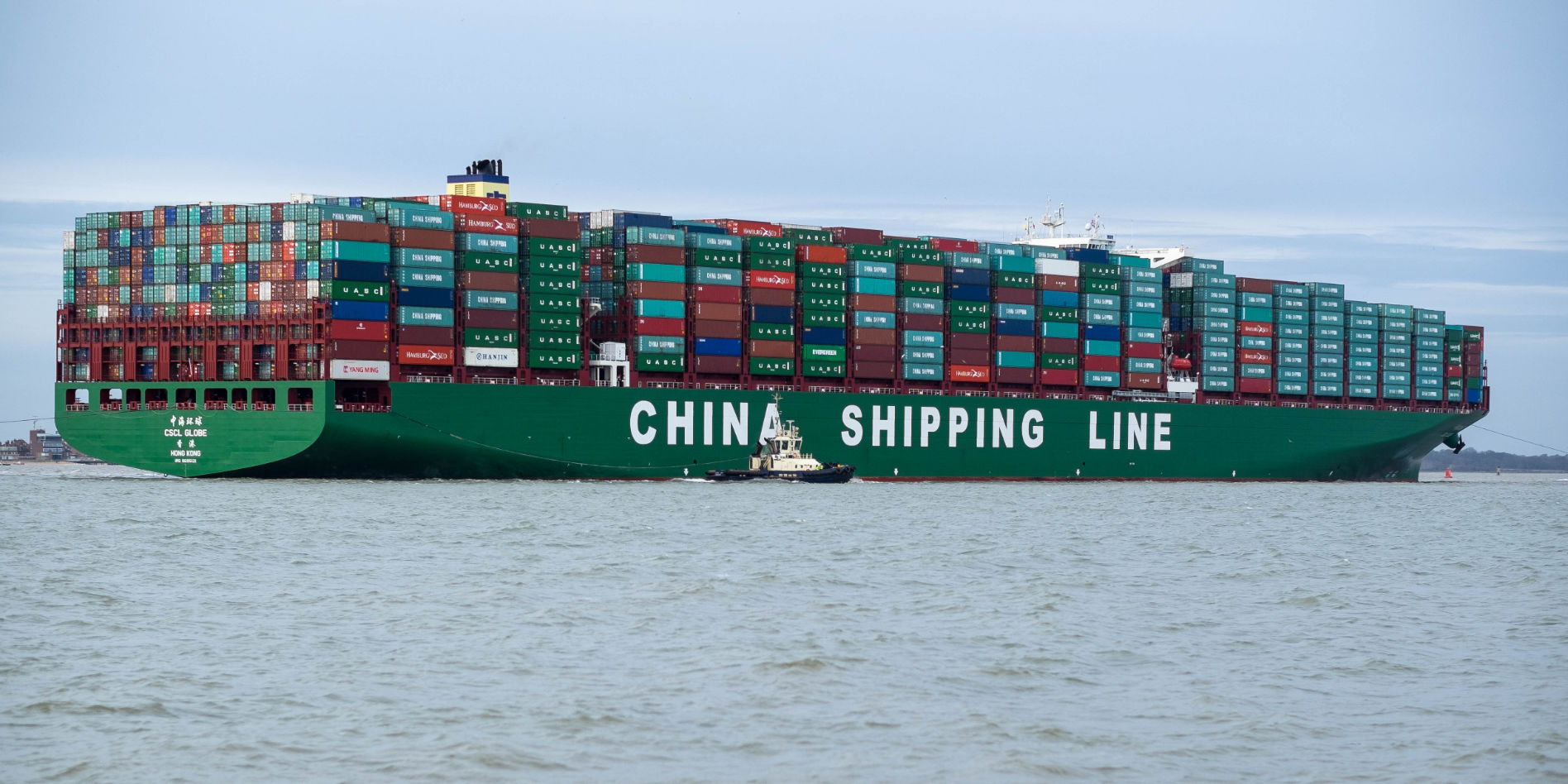 Massive China Shipping Line cargo ship entering U.S. port with hundreds of containers stacked on board