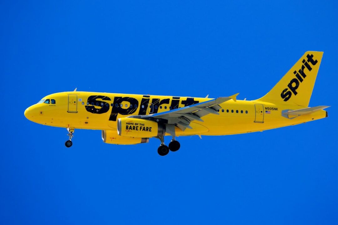 Spirit Airlines yellow airplane in flight under blue sky