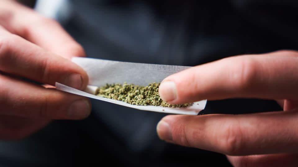 Close-up of a confused man holding a joint while reading health warning