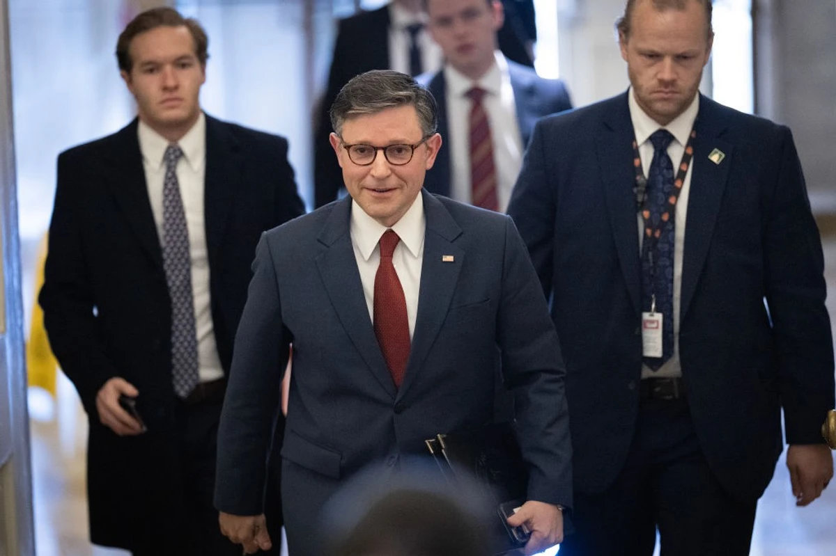 Speaker Mike Johnson walks through Capitol hallway surrounded by aides