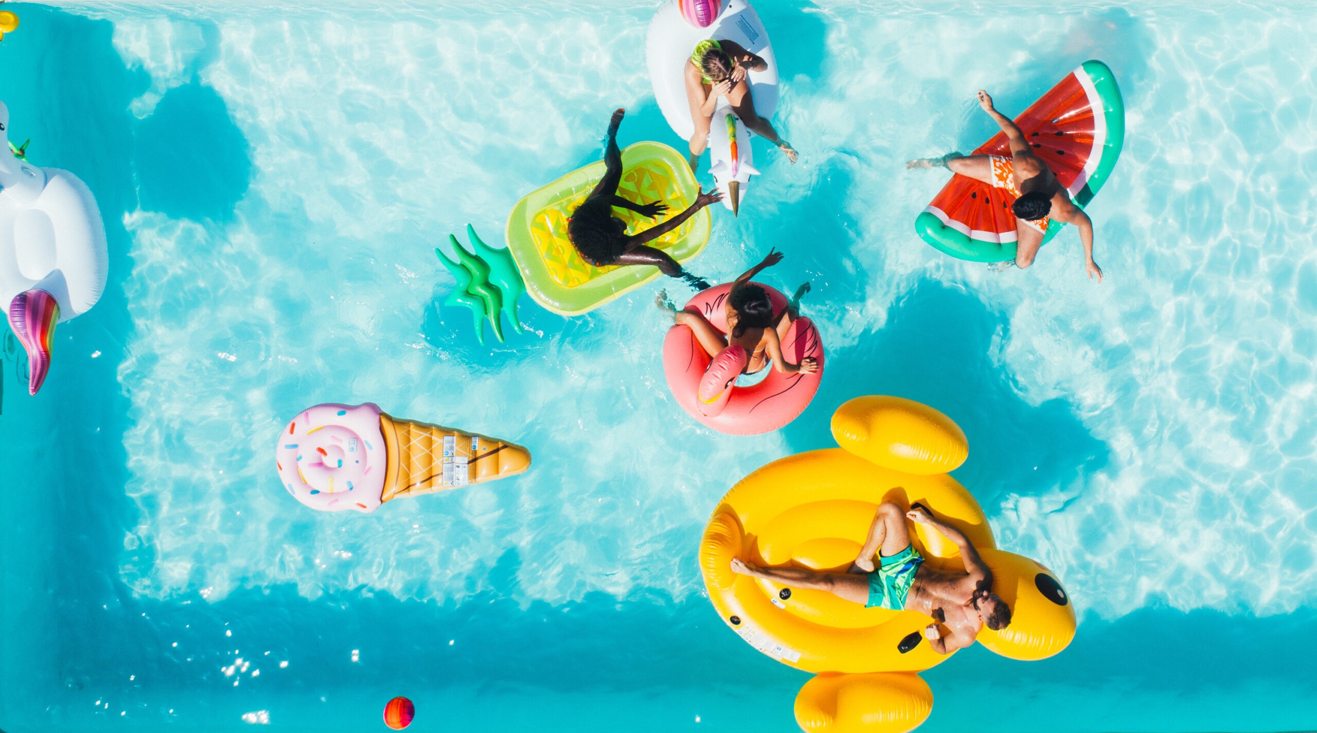 Overhead photo of people in a pool floating on fun floats.