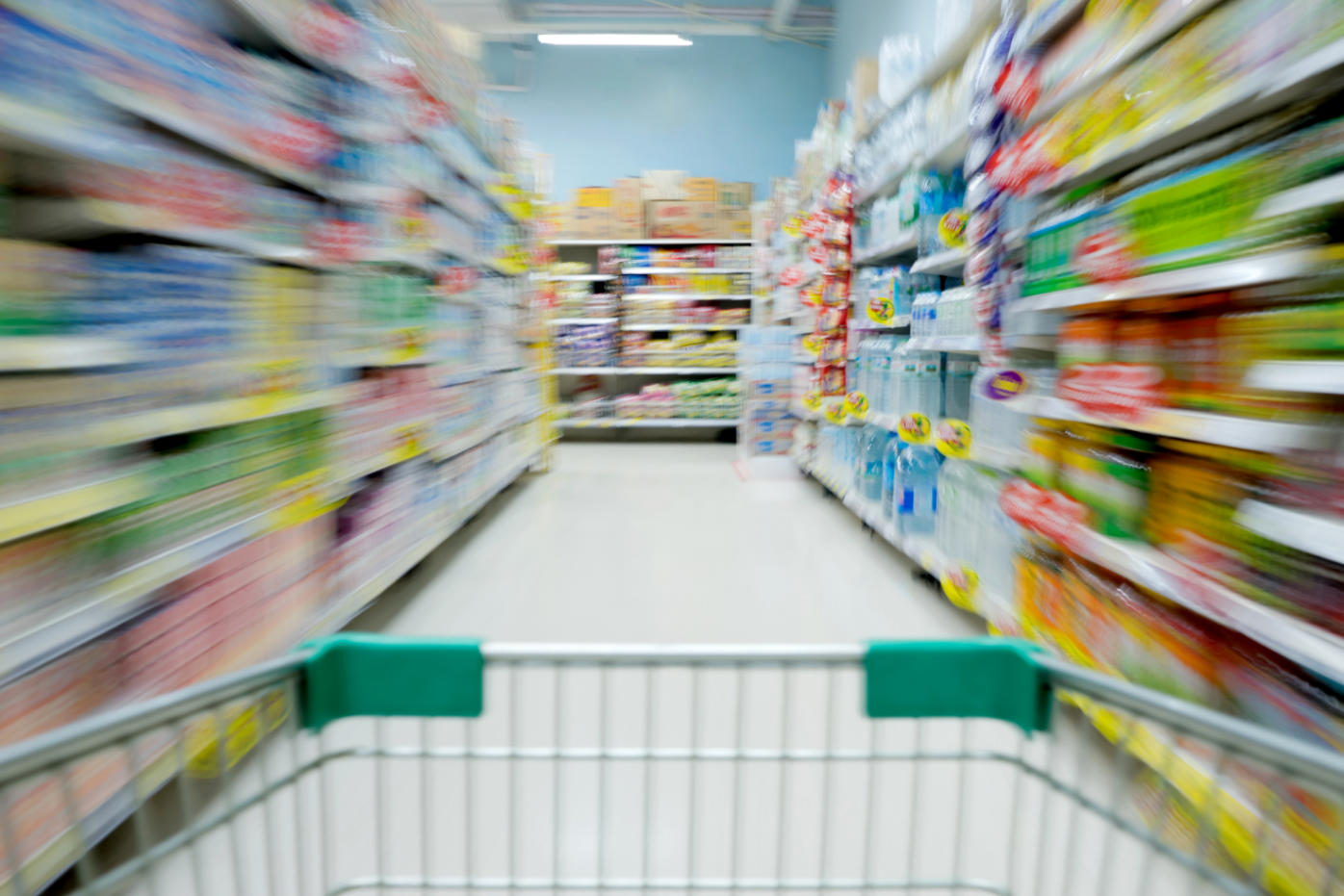 Blurred supermarket aisle seen from shopping cart, symbolizing economic confusion