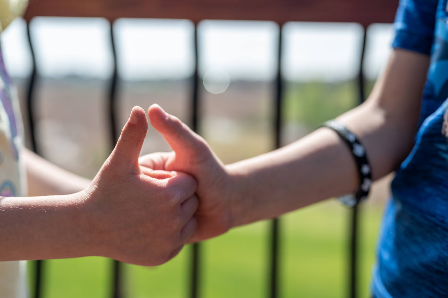 Two people locking thumbs in a game of thumb war outdoors