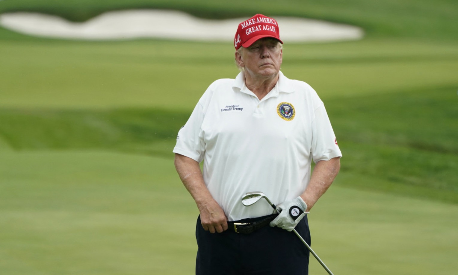 Donald Trump on golf course in red MAGA hat