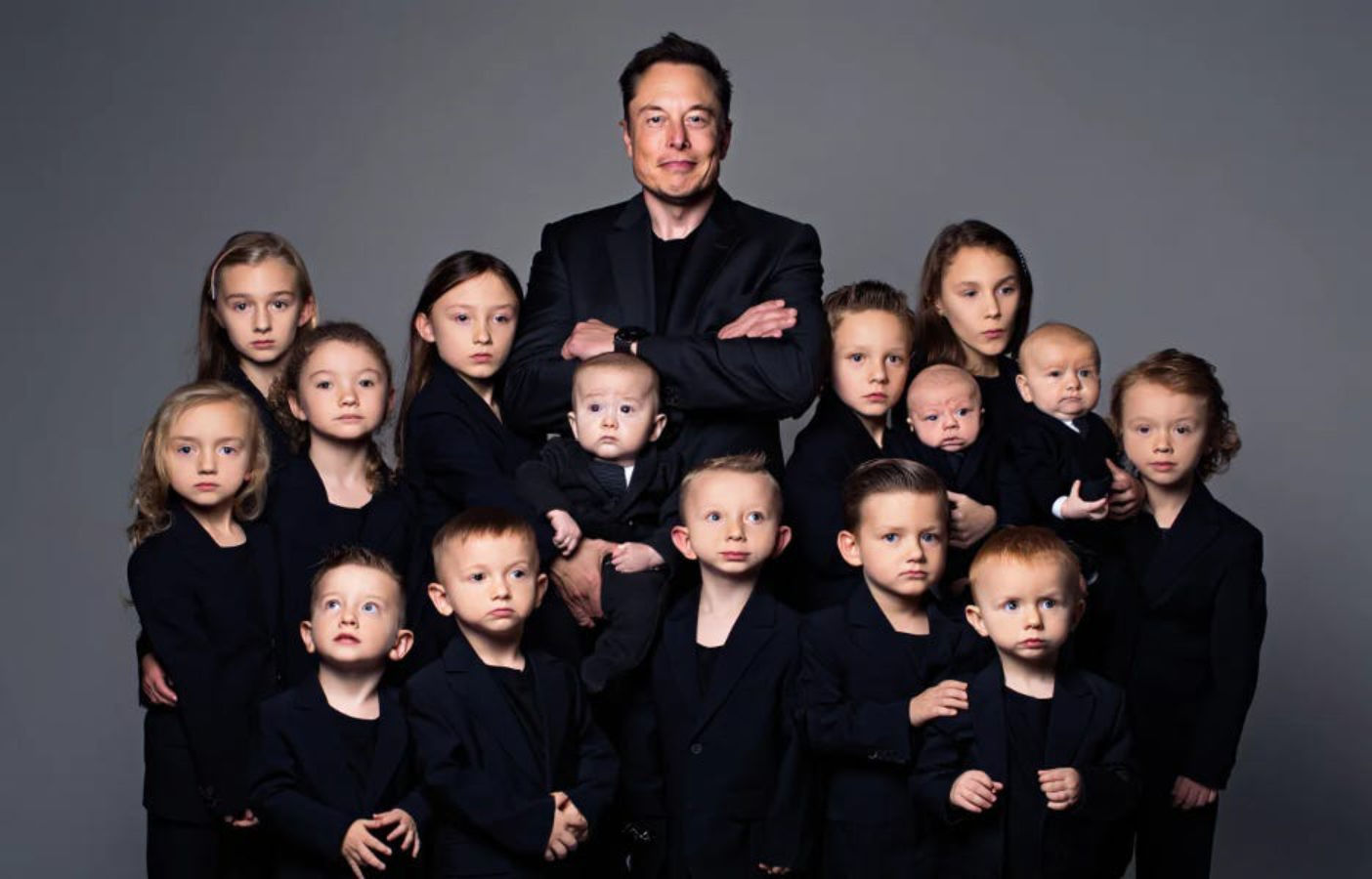 Elon Musk posing with large group of children wearing matching black outfits