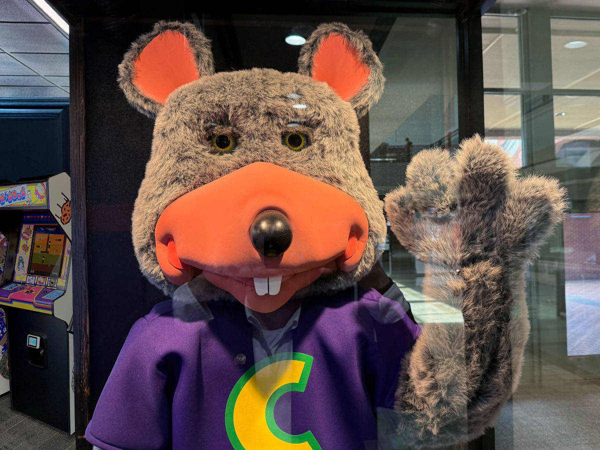 Chuck E. Cheese mascot being arrested by police officer inside restaurant