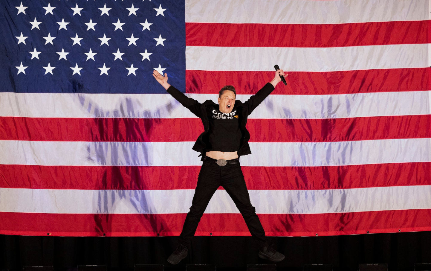 Elon Musk jumping in front of American flag during America Party launch