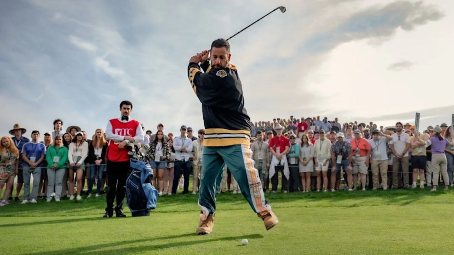 Adam Sandler mid-swing as Happy Gilmore on a crowded golf course