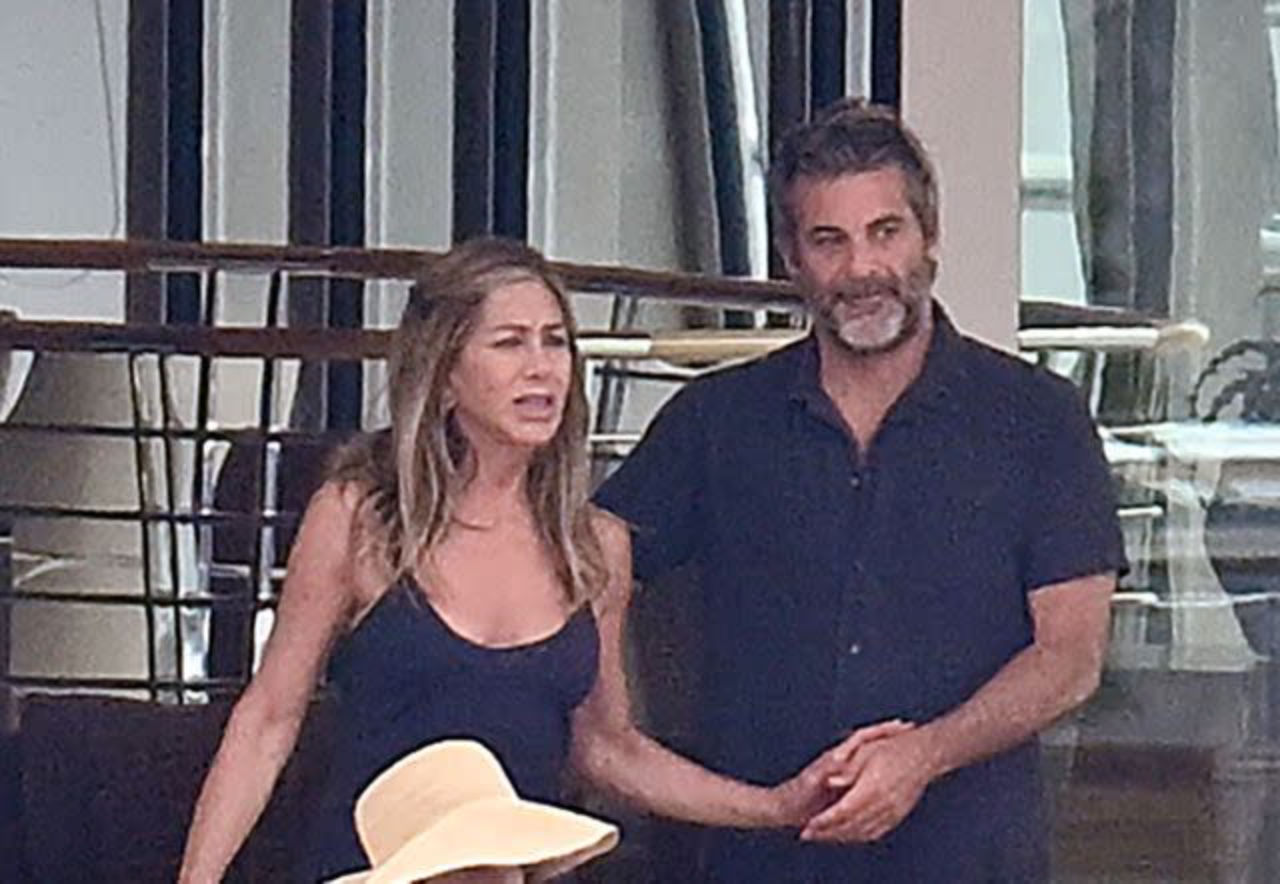 Jennifer Aniston and Jim Curtis holding hands aboard a luxury yacht