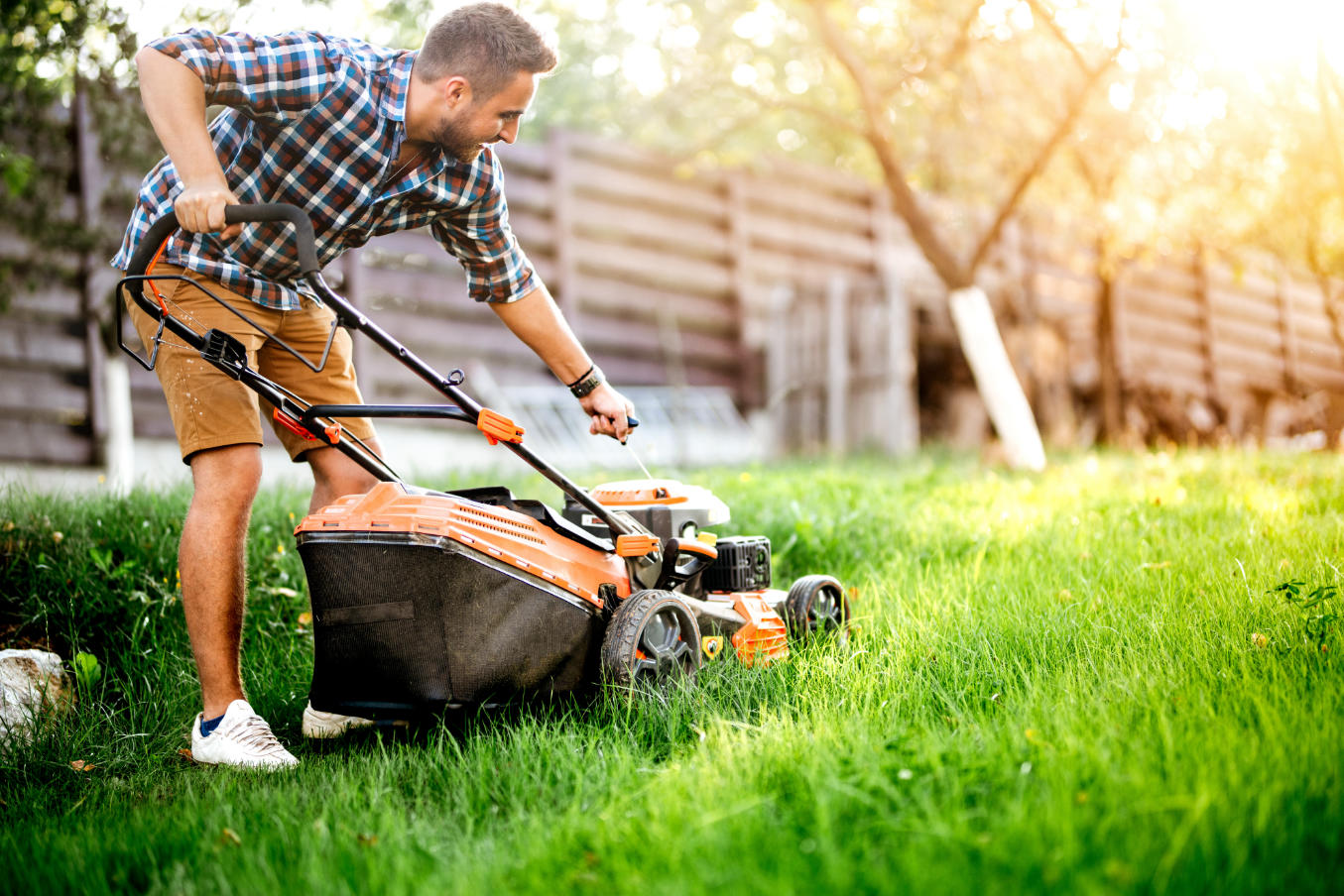 Man mowing lawn with shirt on in backyard