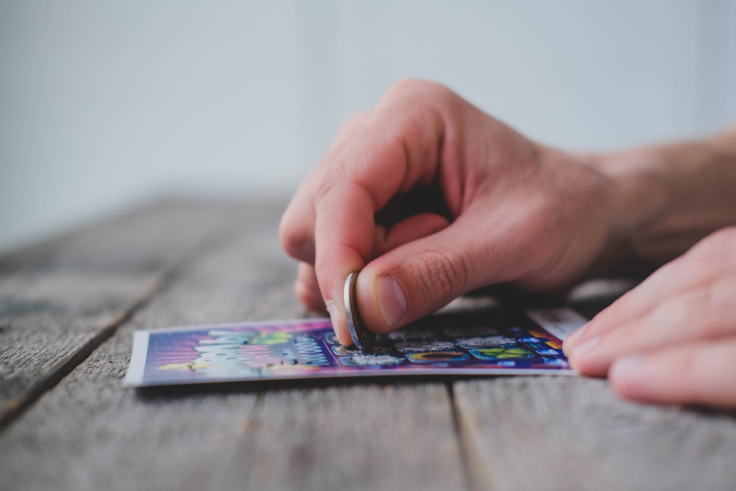 Close-up of man scratching off lottery ticket with a coin