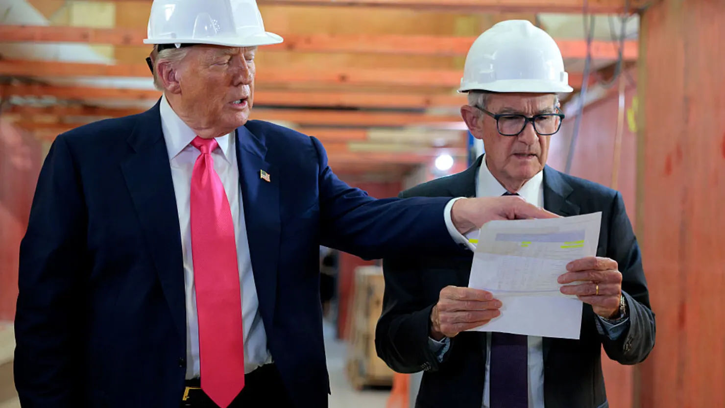 Trump and Jerome Powell wearing hard hats and reviewing renovation blueprints during Federal Reserve site visit