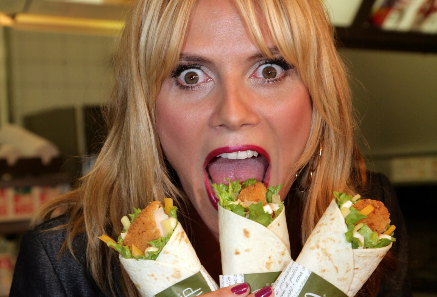 Woman with shocked expression holding three McDonald’s Snack Wraps near her open mouth