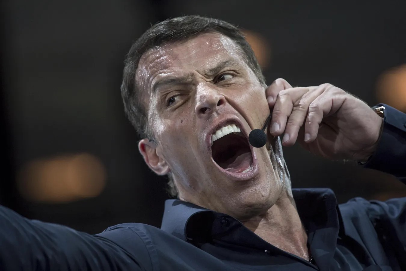 Tony Robbins yelling into headset microphone during motivational seminar