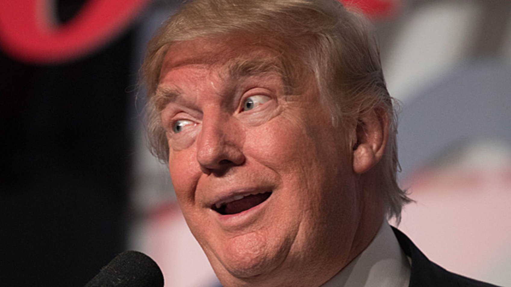 Donald Trump making a dumb facial expression at a microphone