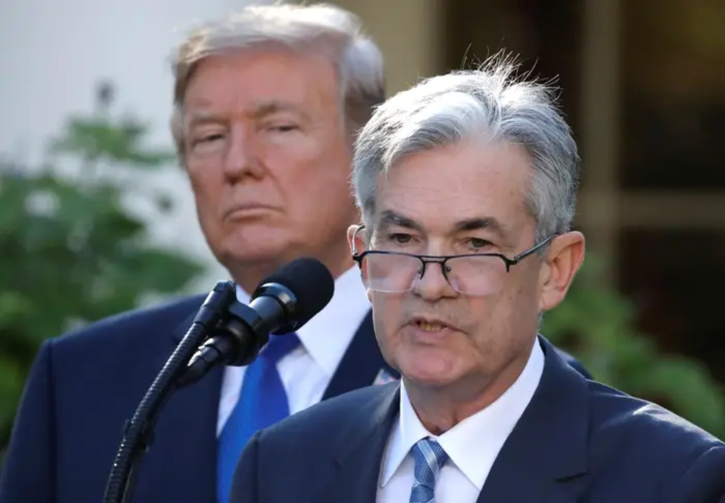 Donald Trump glares behind Jerome Powell during a press conference