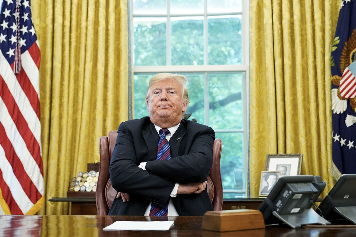 Donald Trump sits with arms crossed at Oval Office desk