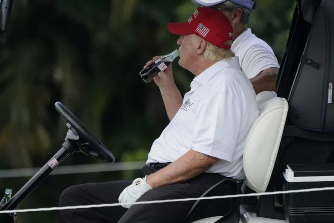 Donald Trump drinking Coca-Cola in a golf cart