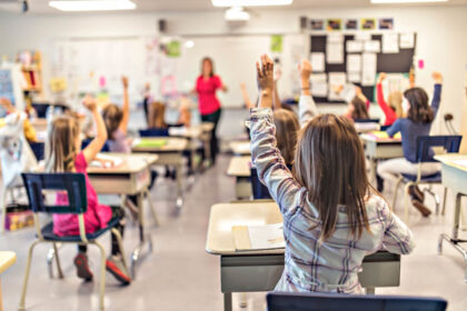 Elementary school students raising hands in classroom