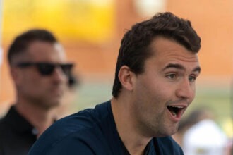 Charlie Kirk speaking outdoors with surprised expression.