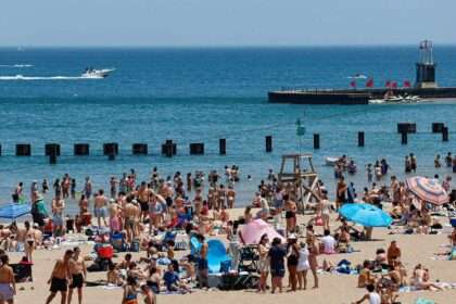 Crowded beach with swimmers in the water despite contamination warnings.