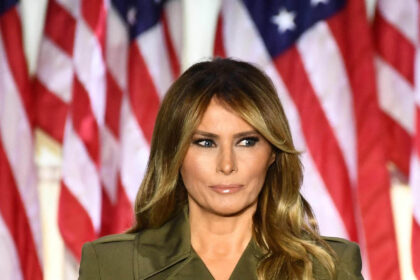 Melania Trump standing in front of American flags