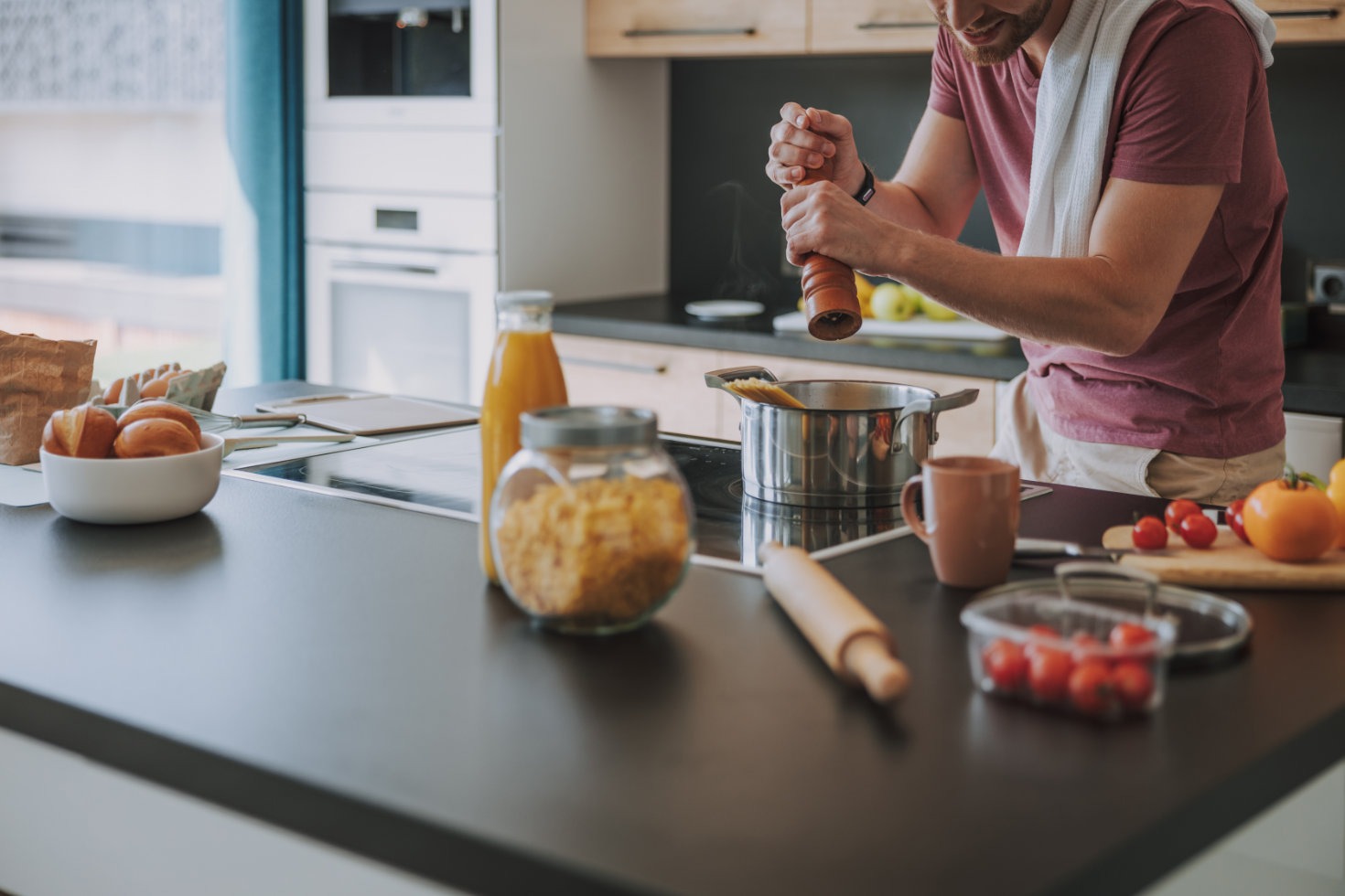 Man cooking pasta in kitchen with groceries on counter