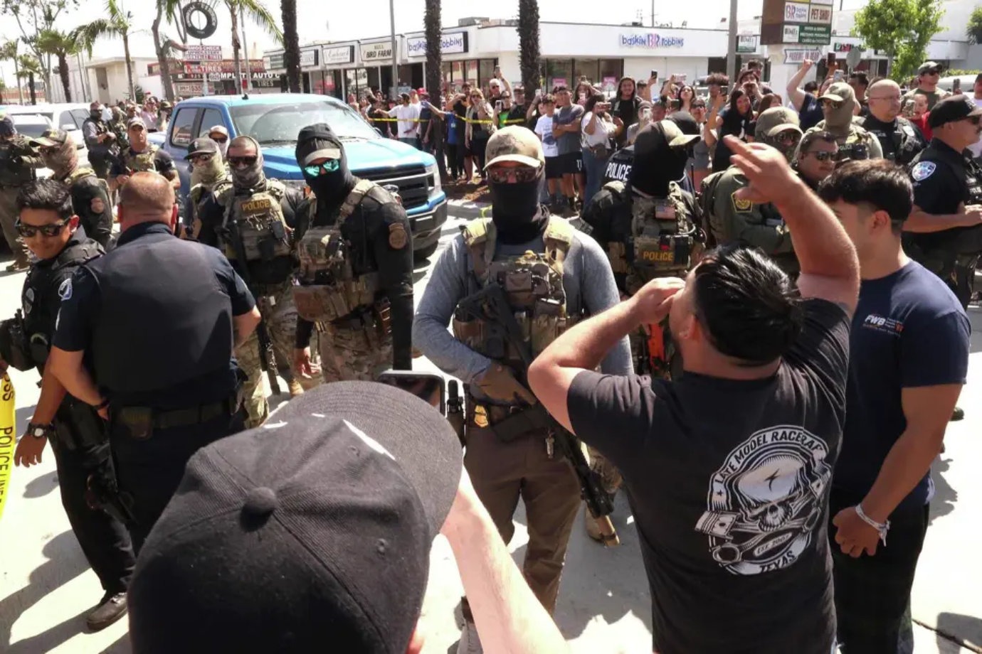 ICE agents in tactical gear surrounded by protesters during Los Angeles workplace raid