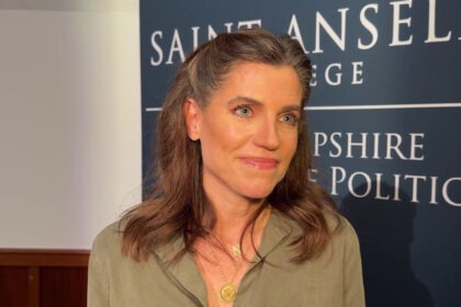 Nancy Mace standing in front of Saint Anselm College backdrop during an interview.
