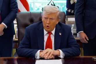 President Donald Trump speaks at the Resolute Desk in the Oval Office.
