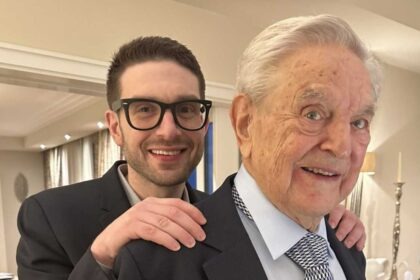 George Soros and Alex Soros posing together in a suit and tie.