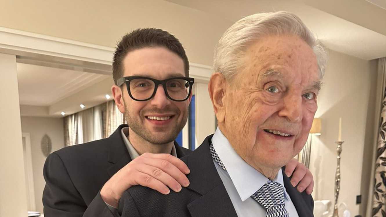 George Soros and Alex Soros posing together in a suit and tie.