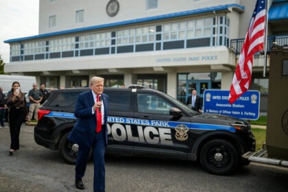 Donald Trump speaking outside United States Park Police station with microphone.