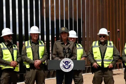 Homeland Security Secretary Kristi Noem speaks in front of border wall construction.