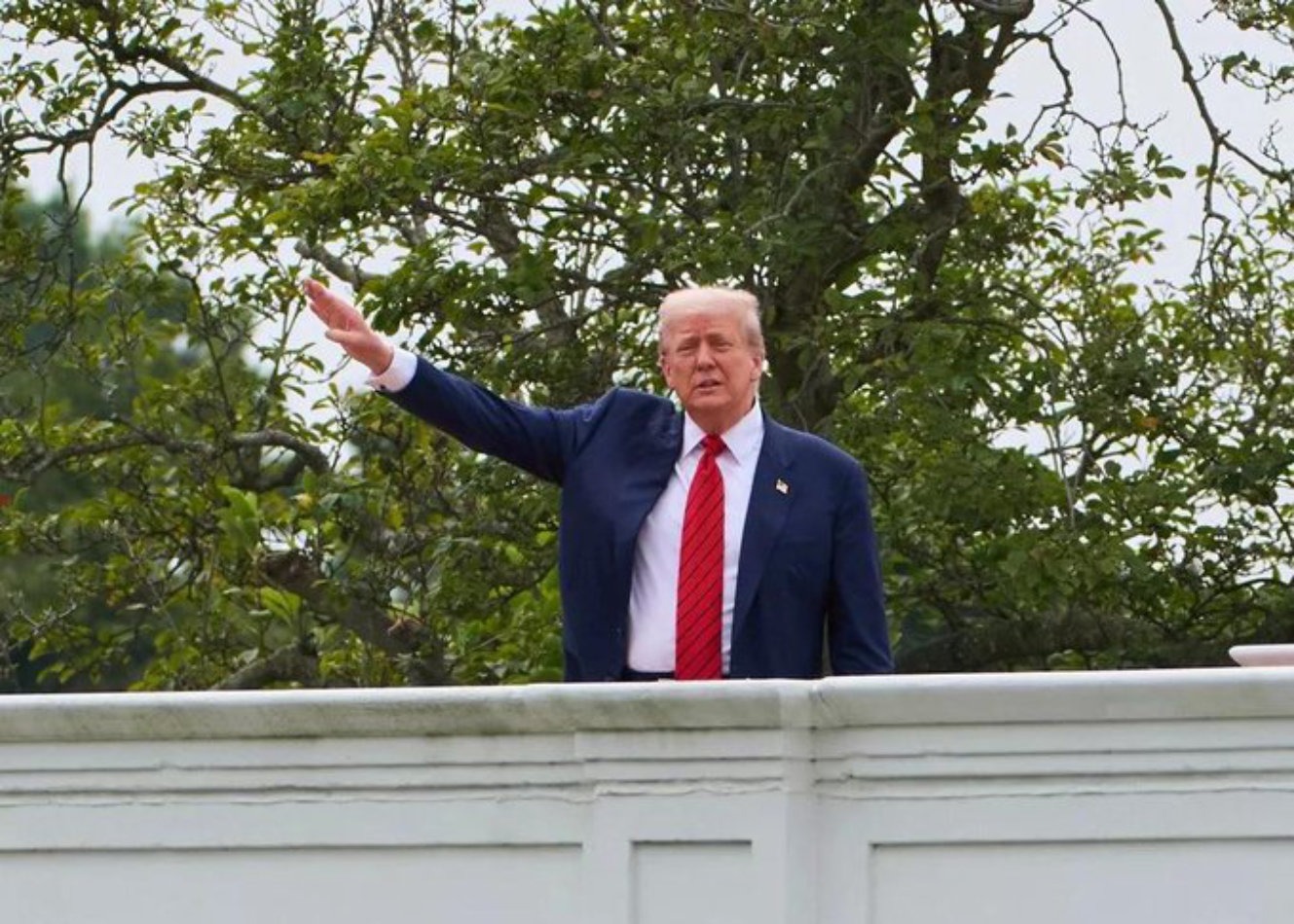 Donald Trump raising an arm from the roof of the White House
