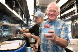 Ben Cohen eating ice cream from a cup at a Ben & Jerry’s event