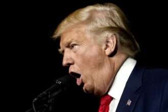 Donald Trump speaking into a microphone during a public appearance