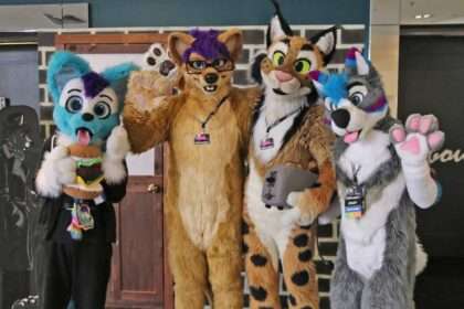 Four furries in colorful animal costumes posing together indoors.