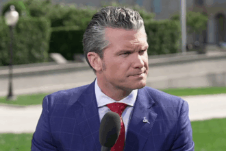 Pete Hegseth speaking outdoors with microphone in hand