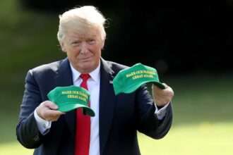 Donald Trump holding green “Make Our Farmers Great Again” hats during trade photo op.