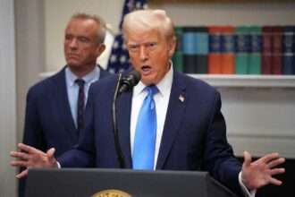 President Donald Trump speaks at a White House press event with Robert F. Kennedy Jr. in the background.