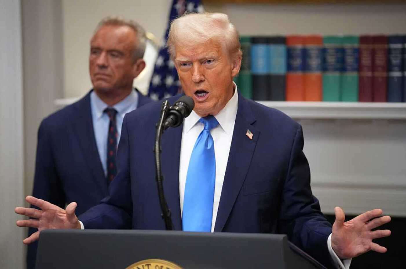 President Donald Trump speaks at a White House press event with Robert F. Kennedy Jr. in the background.