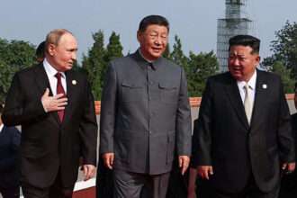 Xi Jinping, Vladimir Putin, and Kim Jong Un talking at a public event in Beijing.