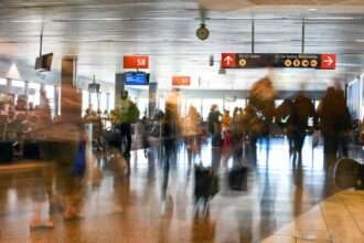 Blurry travelers walking through busy U.S. airport terminal.