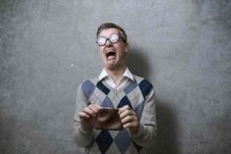 Man with empty wallet expressing shock and frustration.