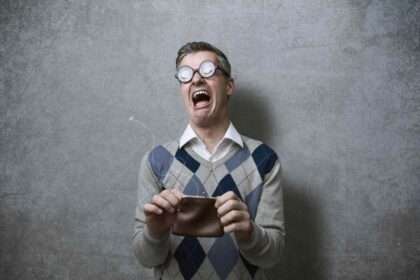 Man with empty wallet expressing shock and frustration.