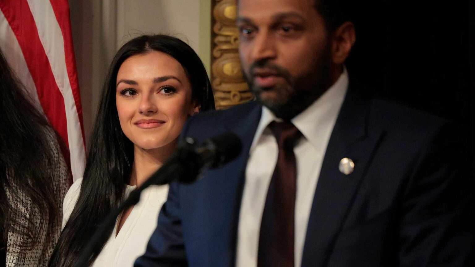 FBI Director Kash Patel speaks at an event as Alexis Wilkins looks on